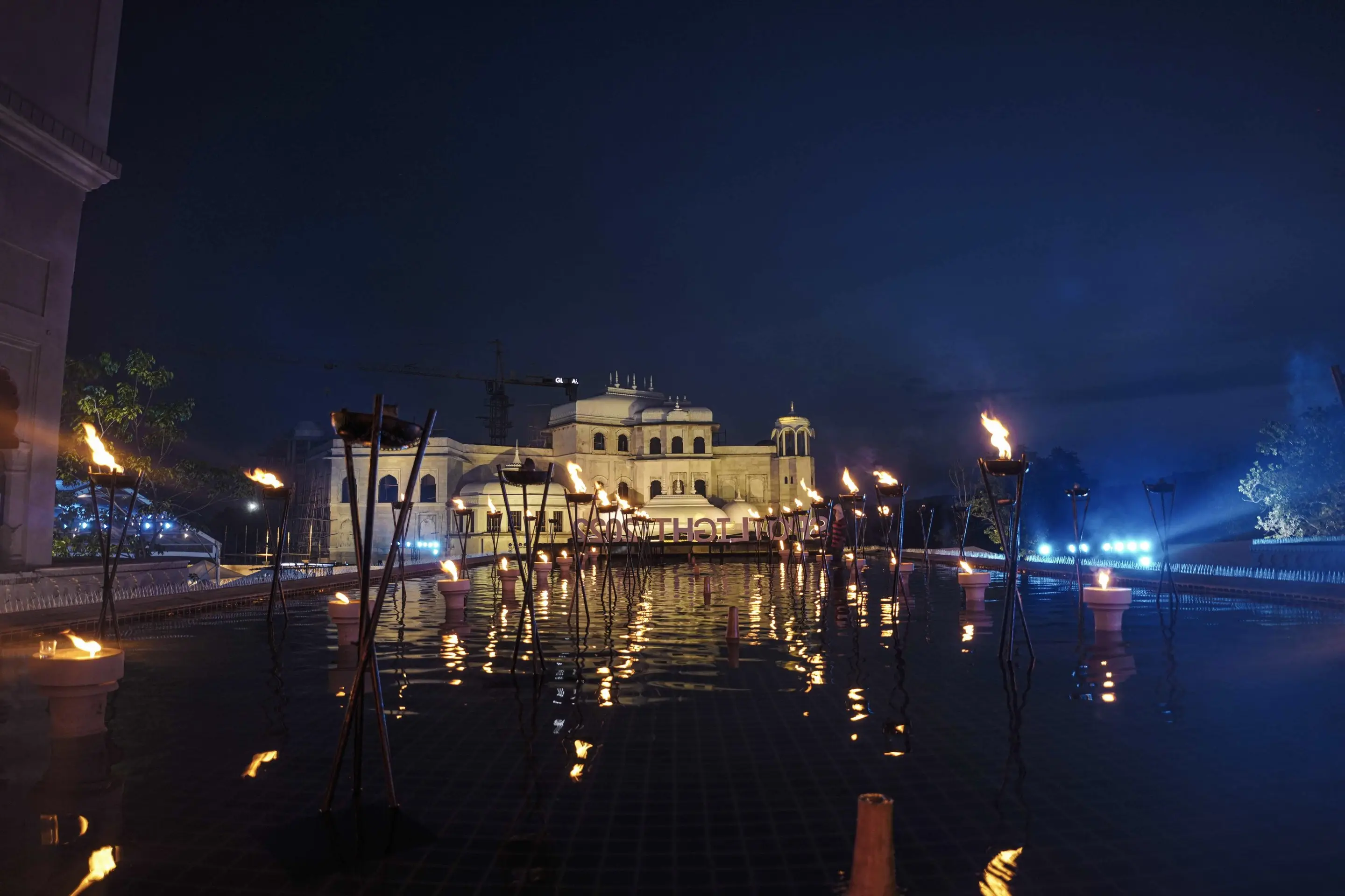 Palace venue at night with torches and lights reflected in a long pool