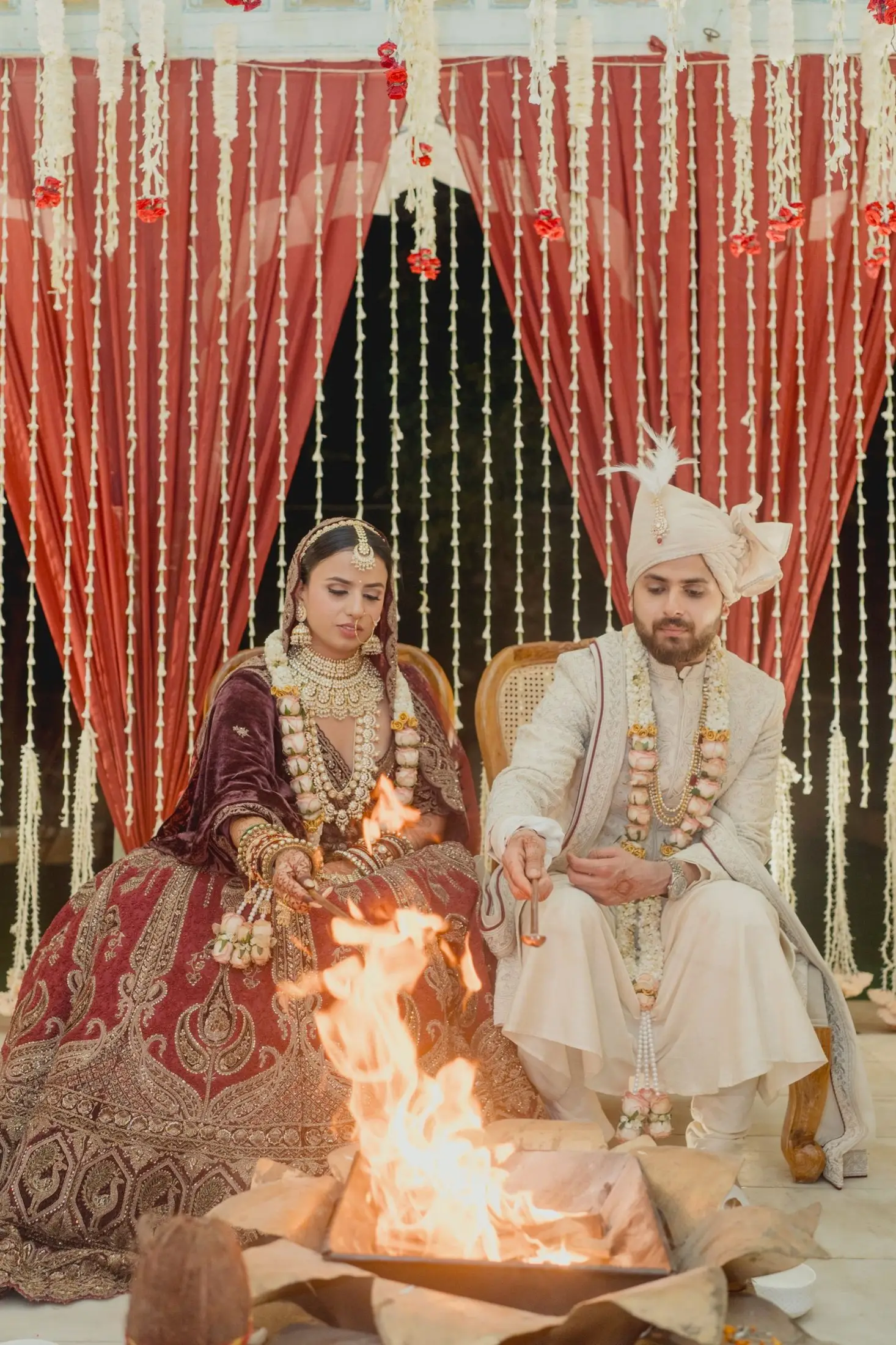 Bride and groom performing the pheras around the sacred fire under a marigold canopy