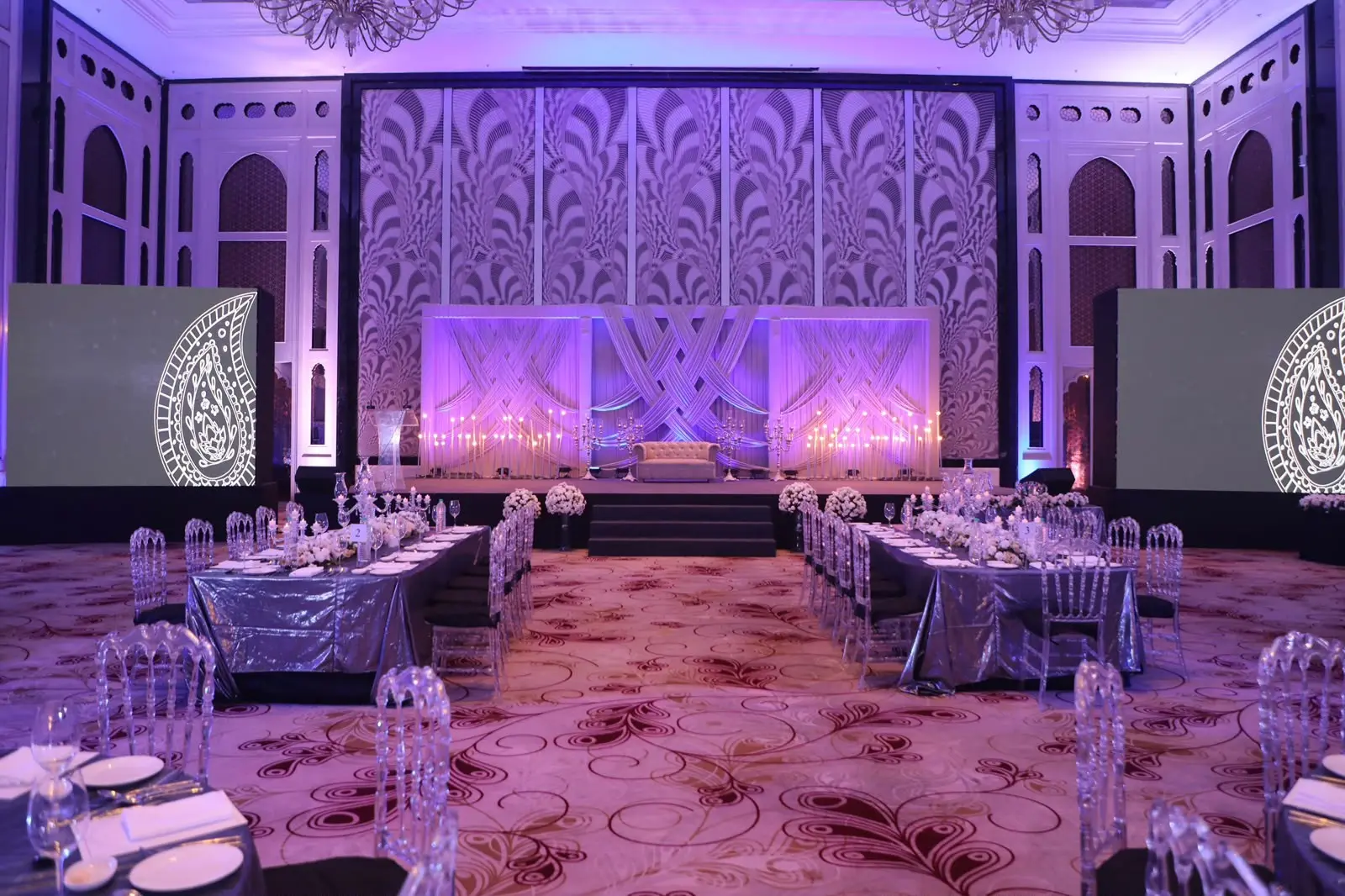 Ballroom set for a reception with long tables and soft purple lighting