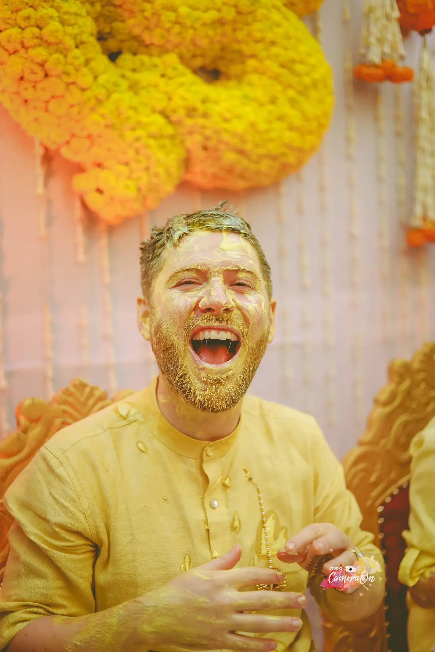 Guest laughing at a haldi ceremony, covered in turmeric