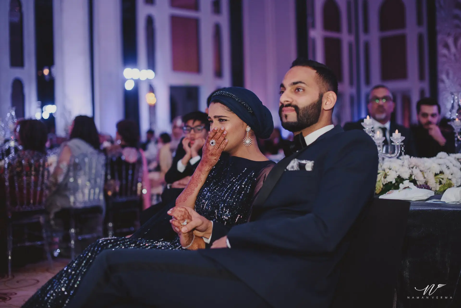 Couple seated at their reception, watching the celebrations